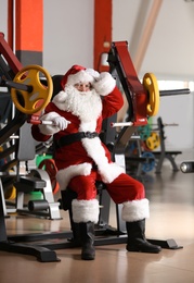 Photo of Authentic Santa Claus resting after exercise in modern gym