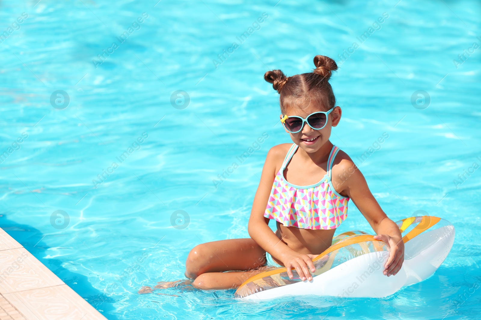 Photo of Cute little girl with inflatable ring in swimming pool