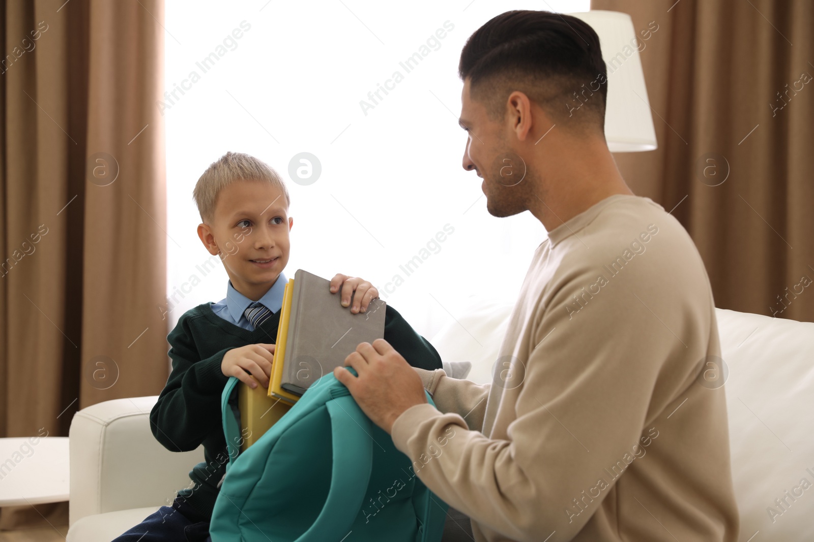 Photo of Father helping his little child get ready for school at home