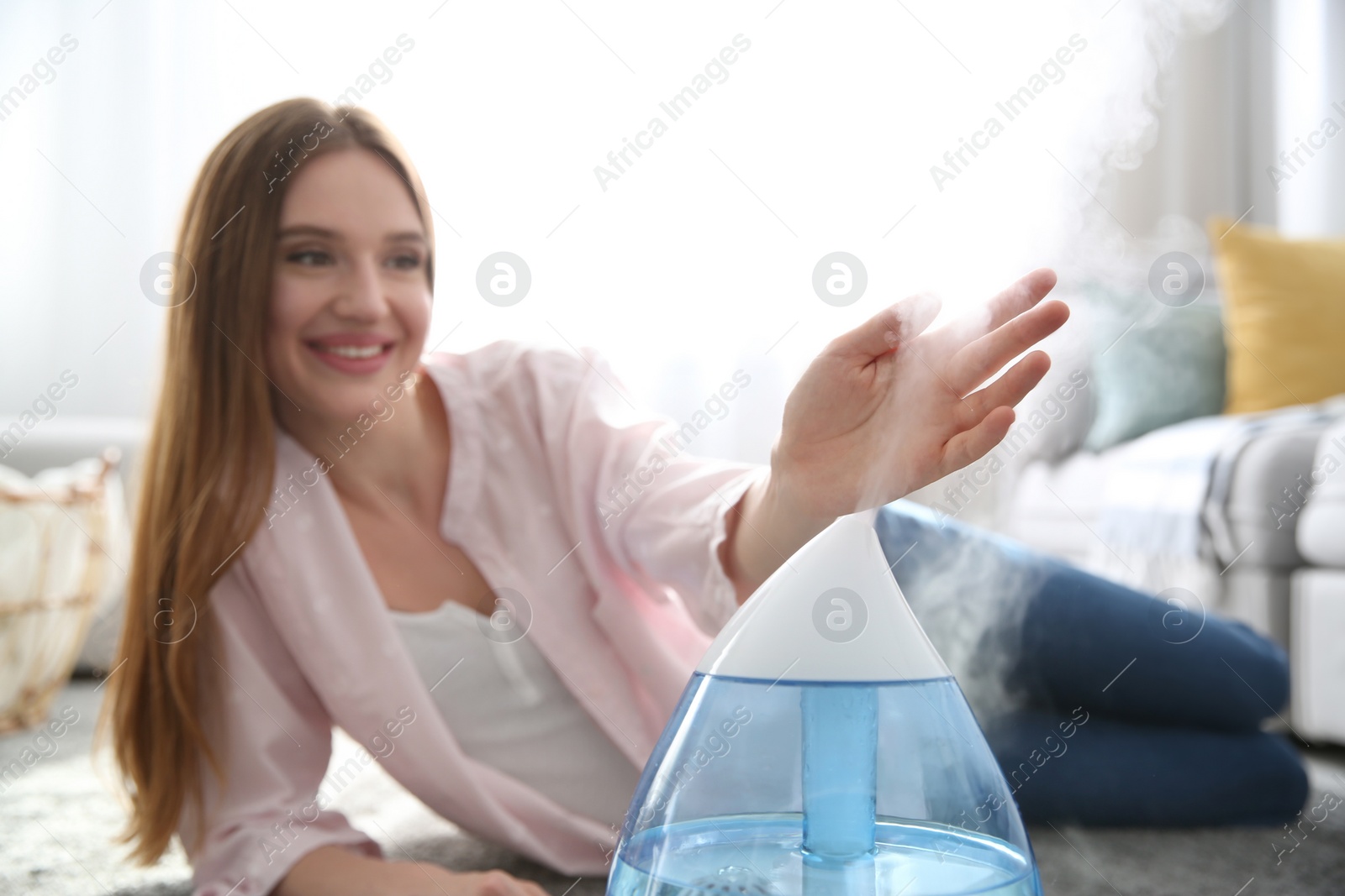 Photo of Woman near modern air humidifier at home