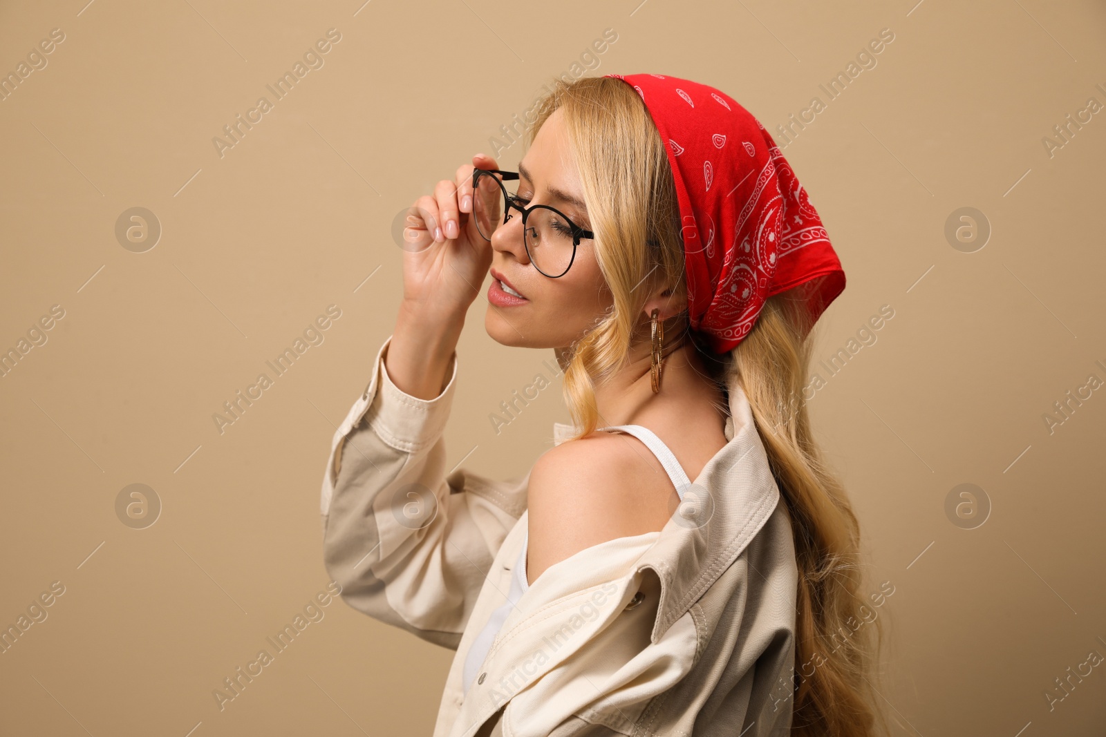 Photo of Young woman with stylish bandana on beige background