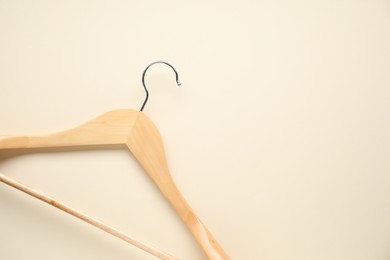 Empty wooden hanger on beige background, top view. Space for text