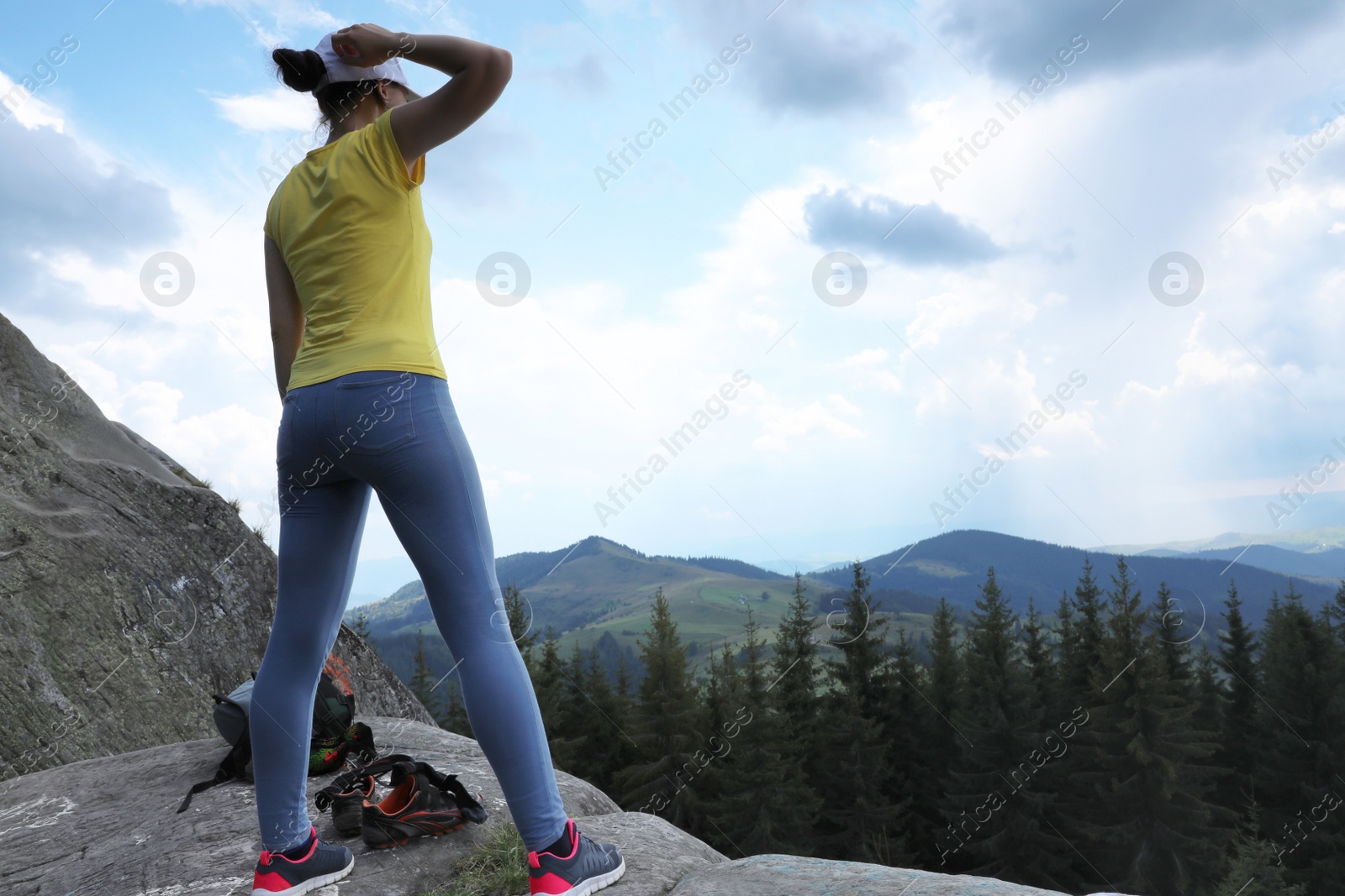 Photo of Female hiker on rocky mountain near forest. Space for text