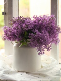 Photo of Beautiful lilac flowers in vase on window sill indoors