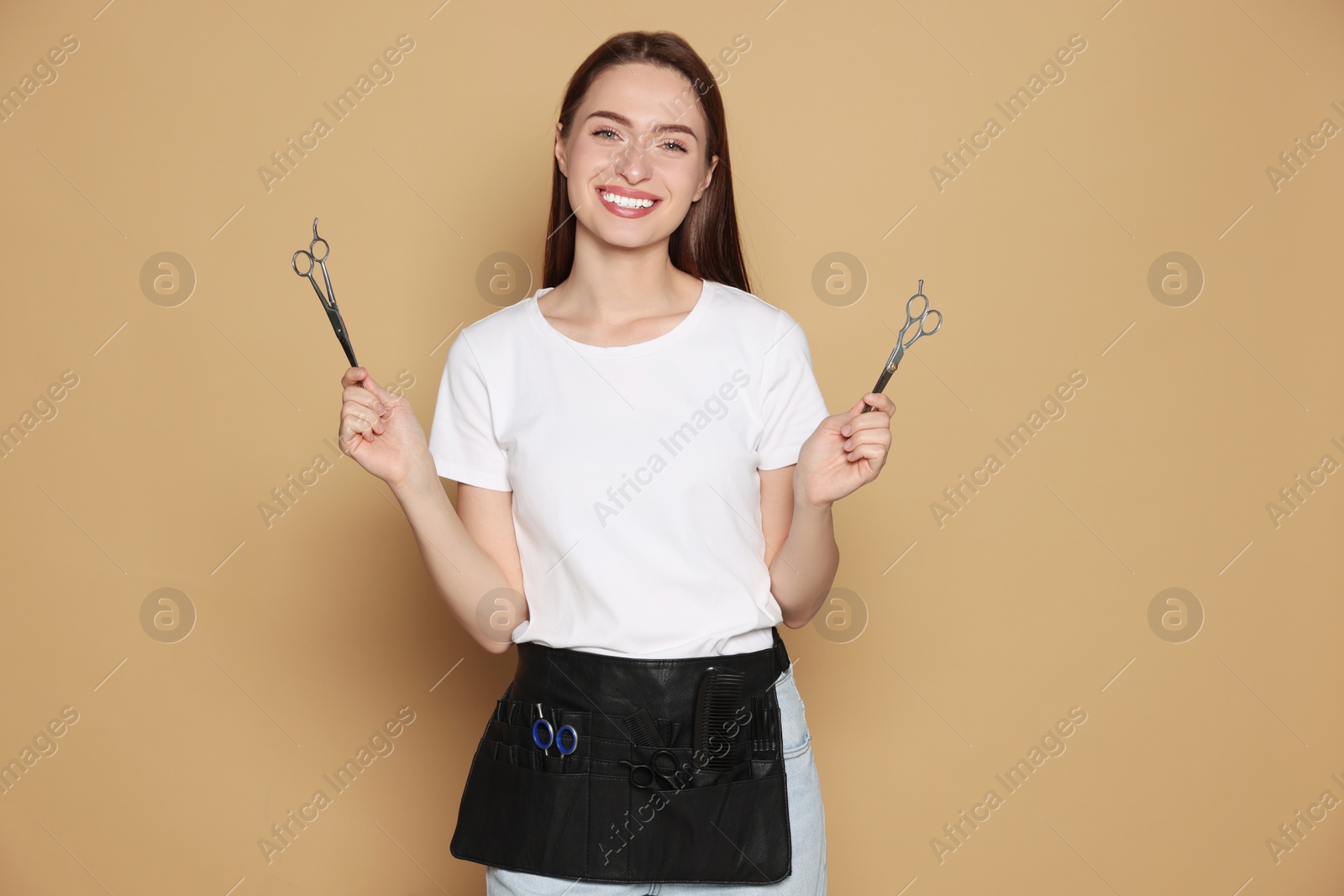 Photo of Portrait of happy hairdresser with professional scissors on beige background