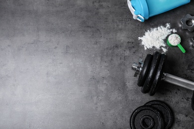 Flat lay composition with protein powder and fitness equipment on grey background. Space for text