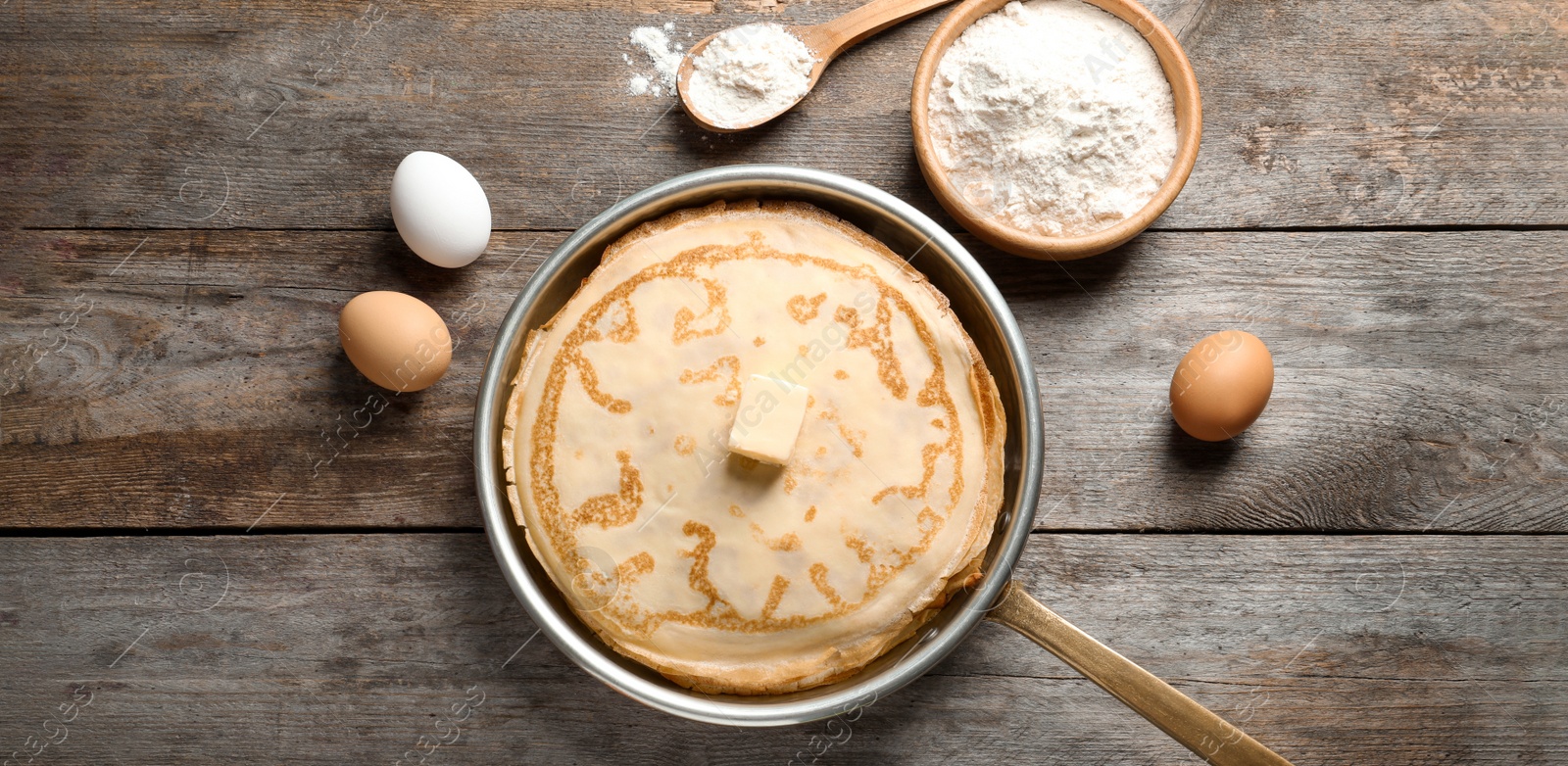 Image of Thin pancakes and ingredients on wooden table, flat lay. Banner design