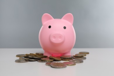 Photo of Pink piggy bank and coins on white table