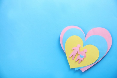 Photo of Paper silhouettes of people and hearts on color background, top view