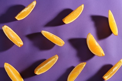Slices of delicious oranges on purple background, flat lay