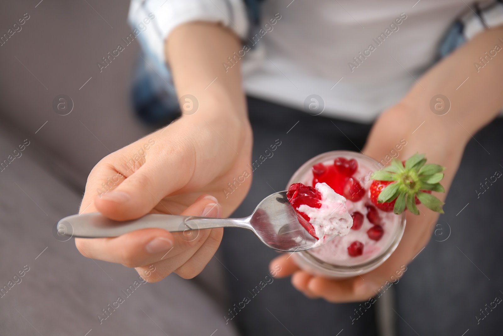 Photo of Young woman eating tasty yogurt with fruits, closeup