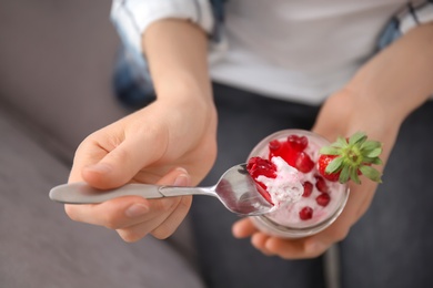 Young woman eating tasty yogurt with fruits, closeup