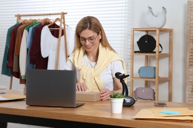 Photo of Seller with parcel and laptop working in office. Online store