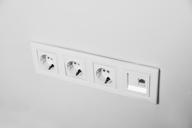 Photo of Power sockets on white wall, closeup. Electrical supply