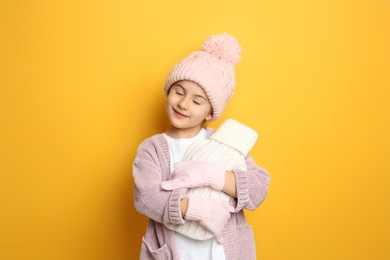 Photo of Ill girl with hot water bottle suffering from cold on yellow background