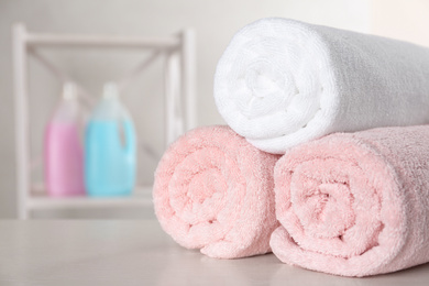 Rolled clean towels on white table in bathroom. Space for text