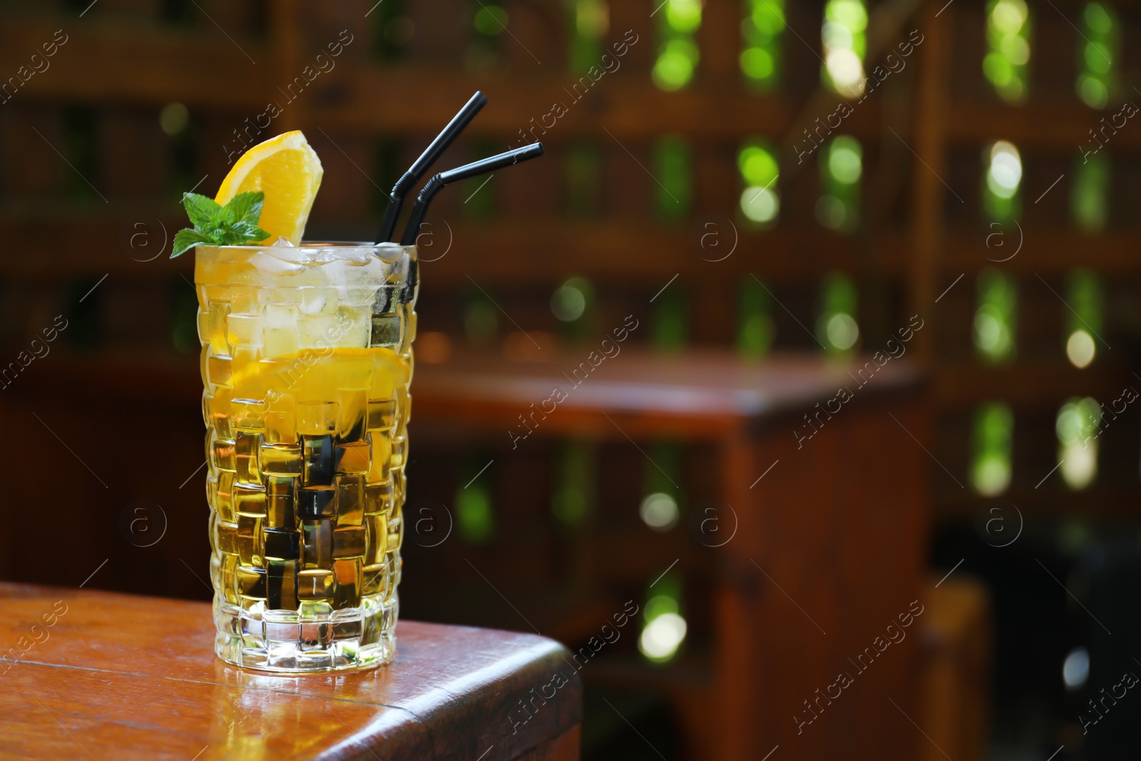 Photo of Glass of delicious cocktail with ice on table in bar