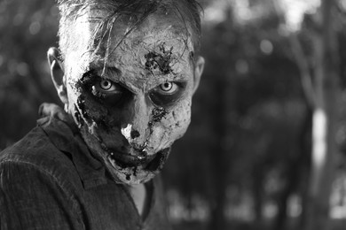 Scary zombie outdoors, black and white effect. Halloween monster