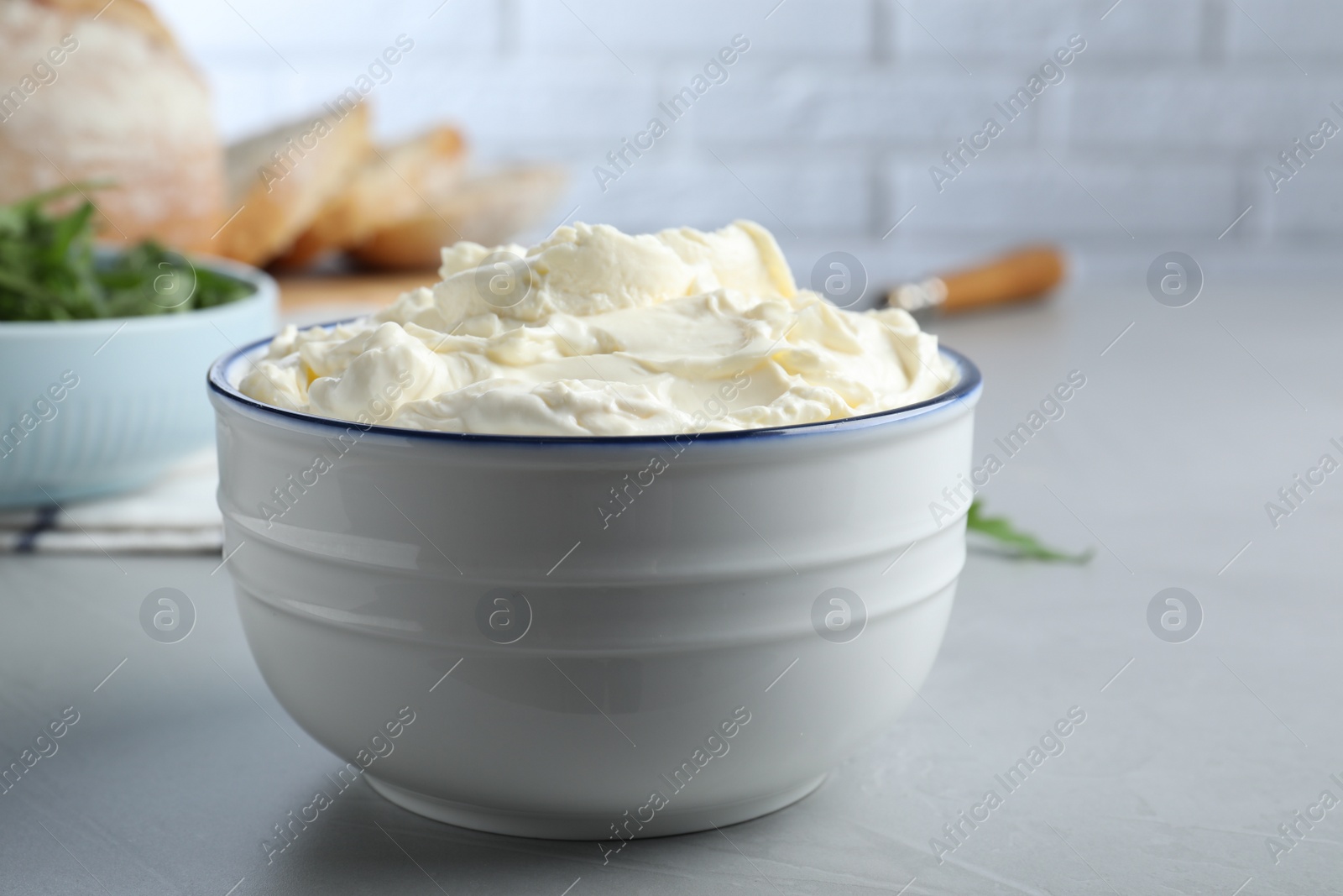 Photo of Bowl of tasty cream cheese on grey table