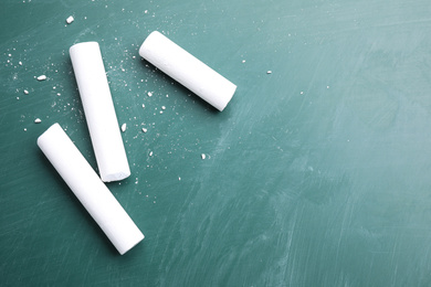 Photo of Pieces of white chalk on greenboard, flat lay. Space for text