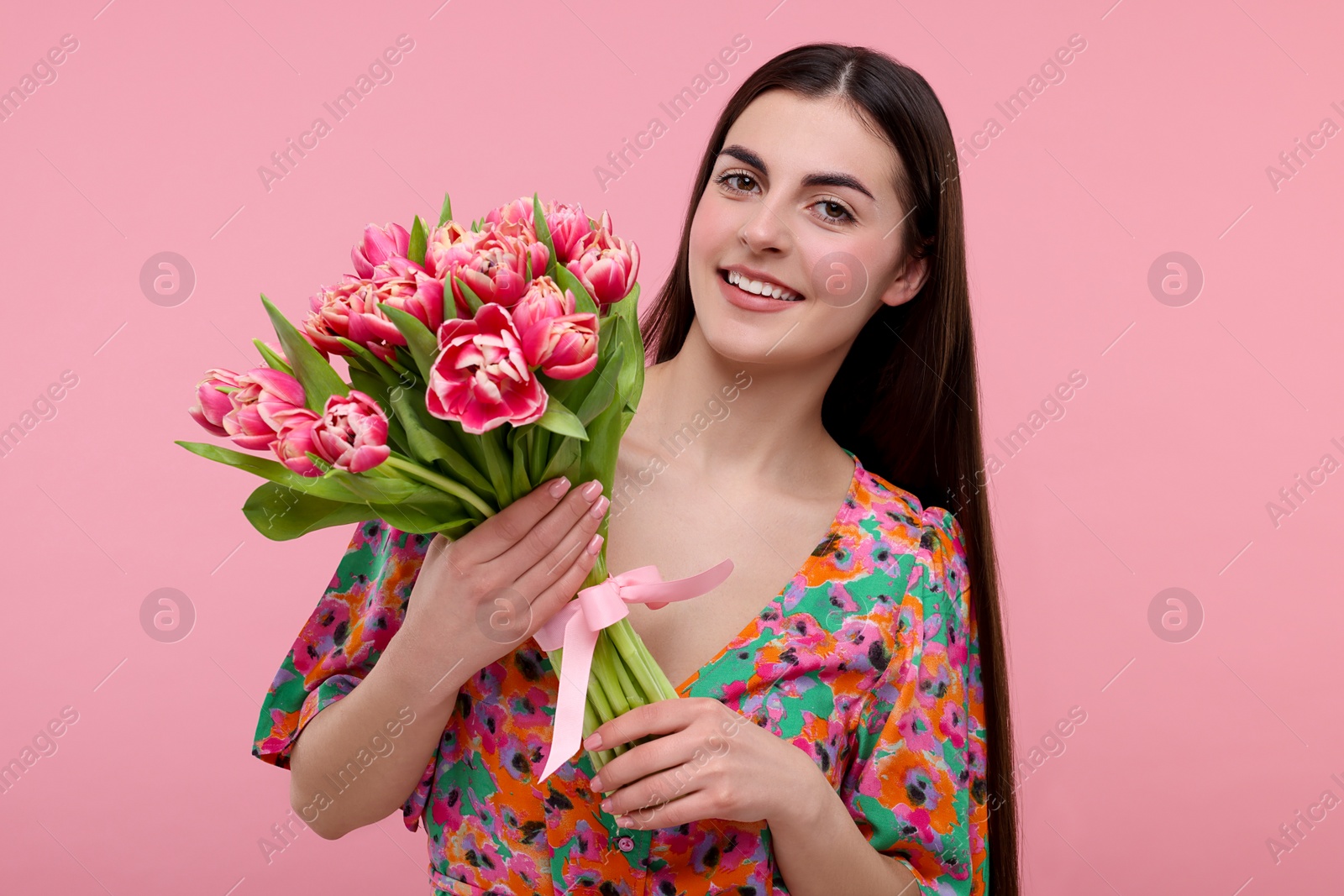 Photo of Happy young woman with beautiful bouquet on dusty pink background