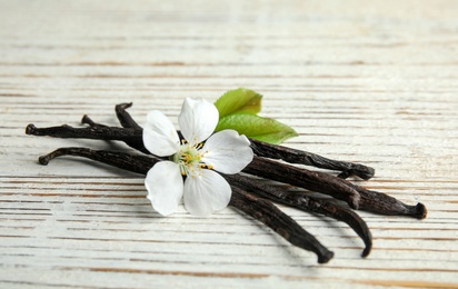 Photo of Aromatic vanilla sticks and flower on wooden background