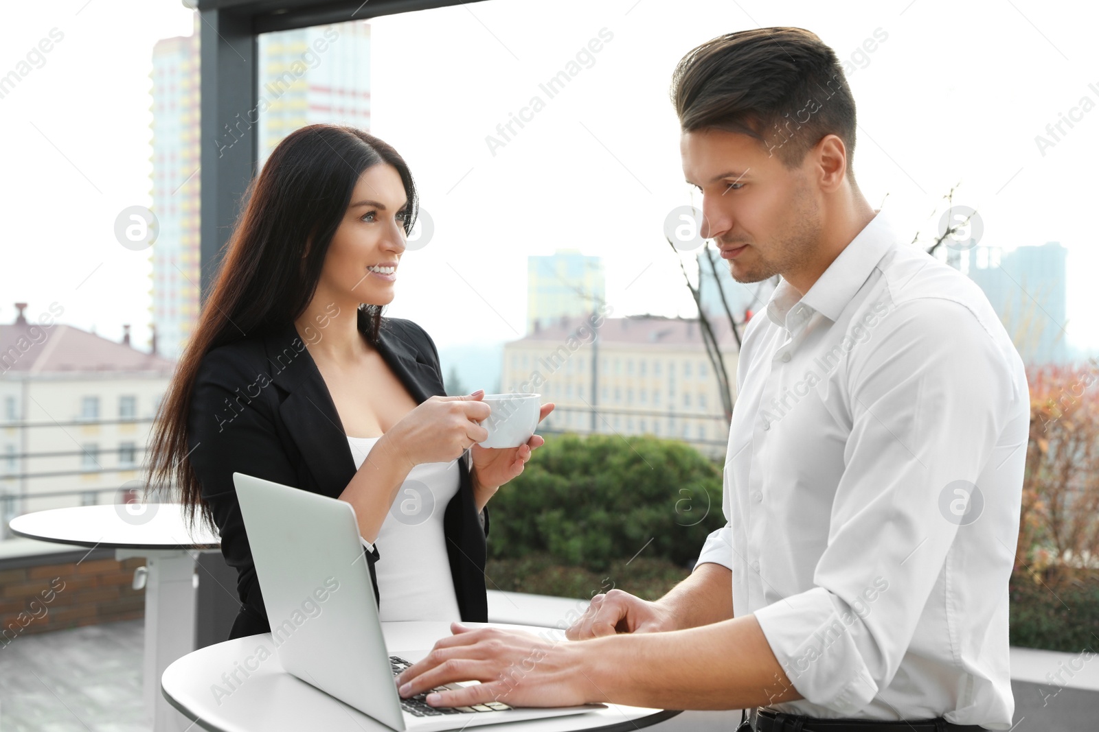 Photo of Business people with laptop in outdoor cafe. Corporate blog