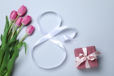 Photo of 8 March greeting card design with tulips, ribbon and gift box on light grey background, flat lay. International Women's day