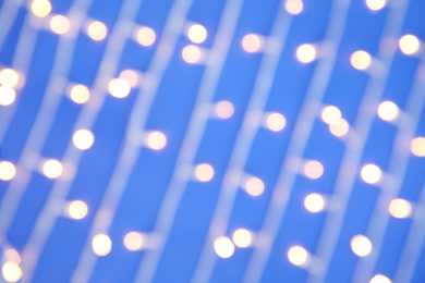 Blurred view of glowing Christmas lights on color background, top view