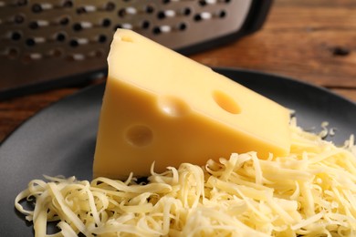 Grated and whole piece of cheese on wooden table, closeup