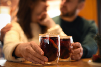 Photo of Couple with tasty mulled wine at table in cafe, closeup. Winter vacation