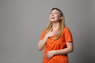 Photo of Beautiful young woman laughing on grey background, space for text. Funny joke