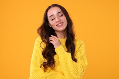 Photo of Beautiful young woman in stylish warm sweater on orange background