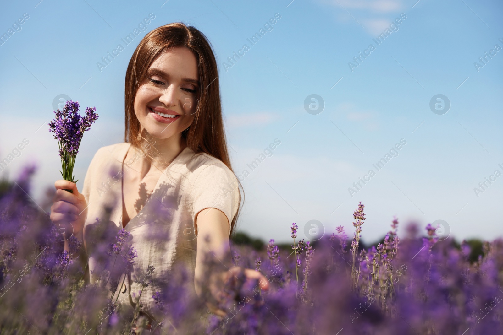 Photo of Young woman with lavender bouquet in field on summer day