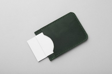 Leather business card holder with blank cards on light grey background, top view
