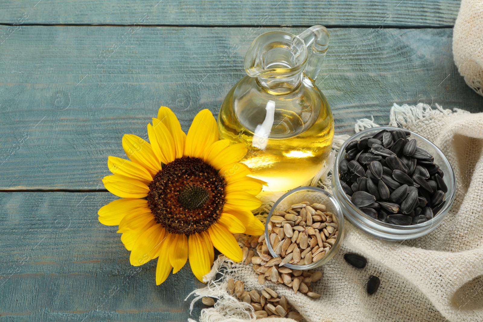 Photo of Sunflower, oil and seeds on light blue wooden table