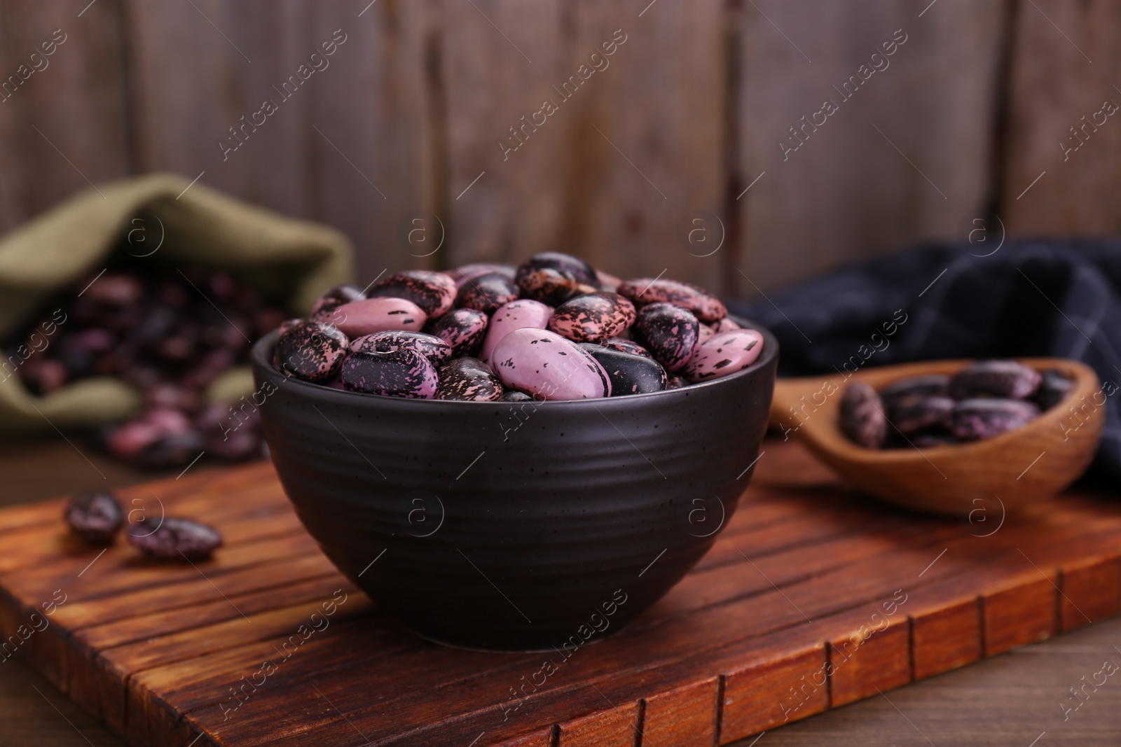 Photo of Bowl with dry kidney beans on wooden table, closeup