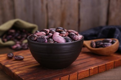 Photo of Bowl with dry kidney beans on wooden table, closeup