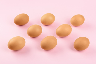 Photo of Raw chicken eggs on pink background, above view