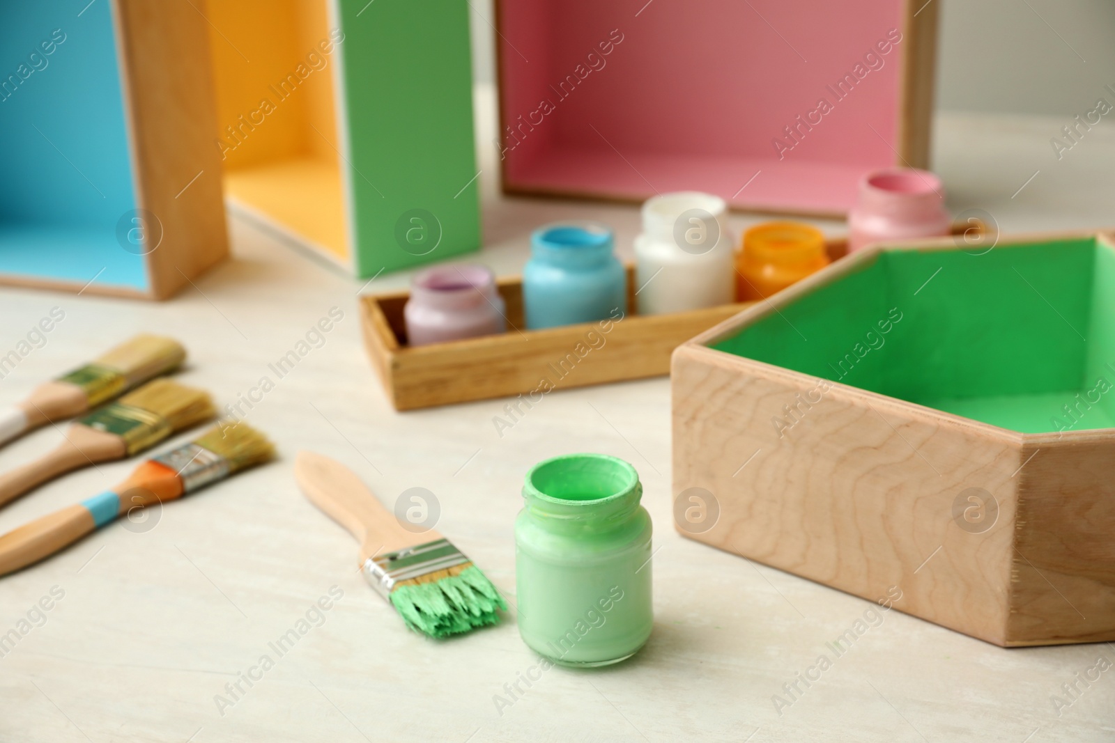 Photo of Jar of green paint and brush on white table