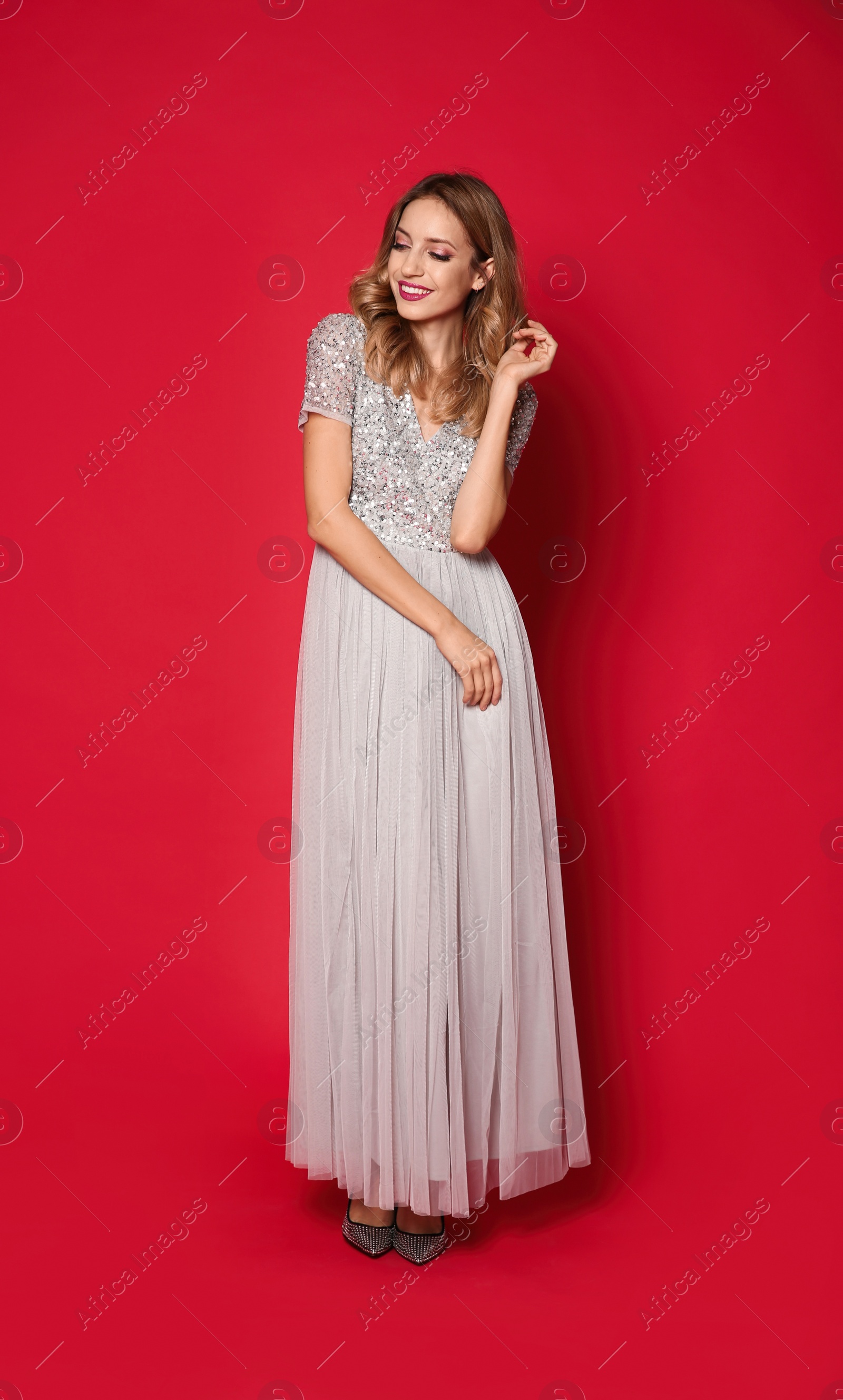 Photo of Happy woman in stylish dress on red background. Christmas party