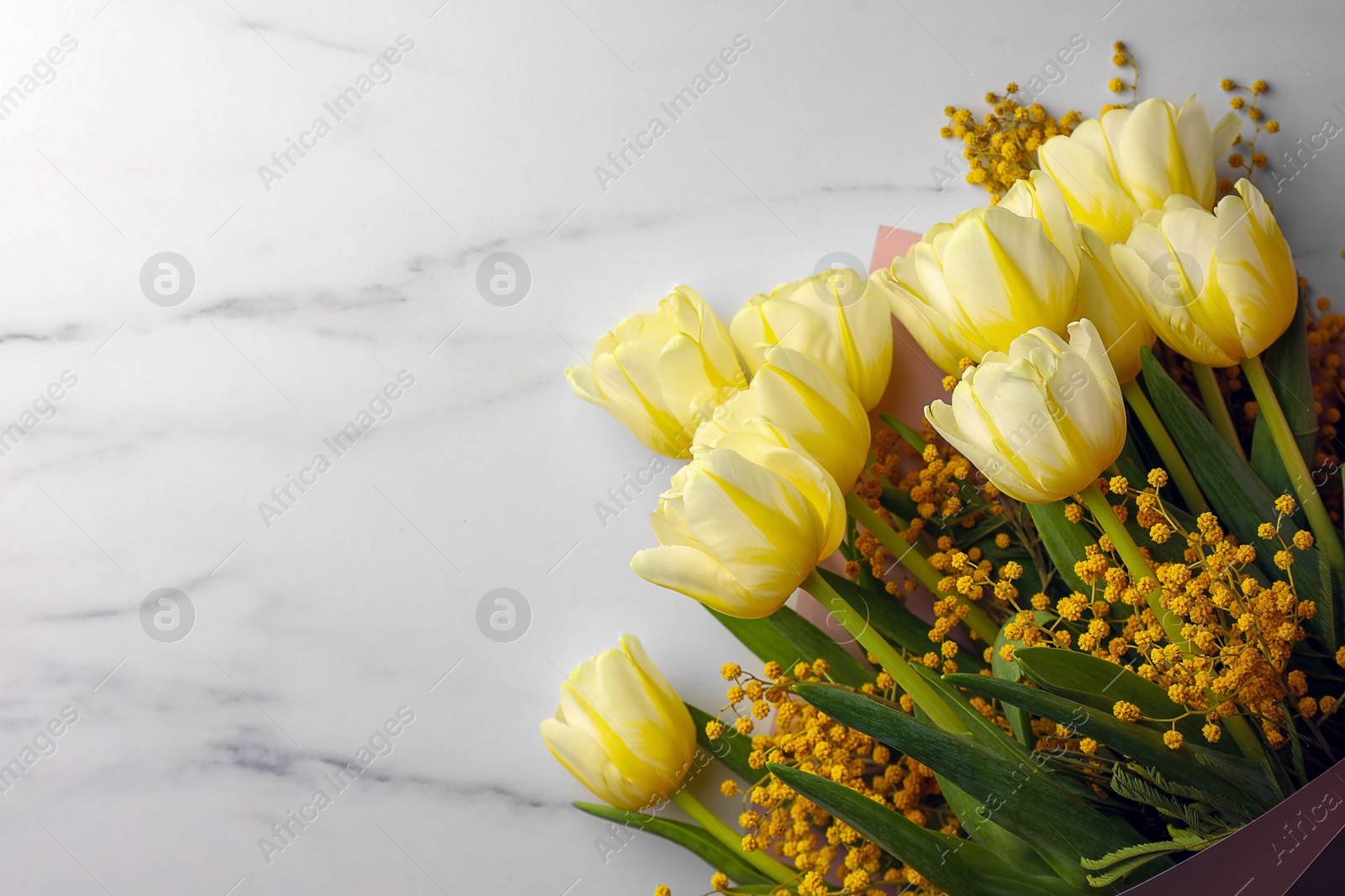 Photo of Bouquet with beautiful tulips and mimosa flowers on white marble table, top view. Space for text