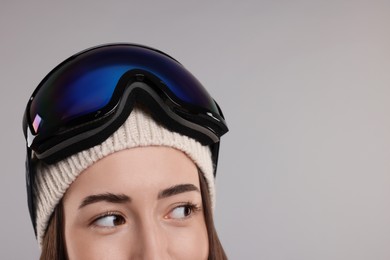 Winter sports. Happy woman with snowboard goggles on grey background, closeup. Space for text