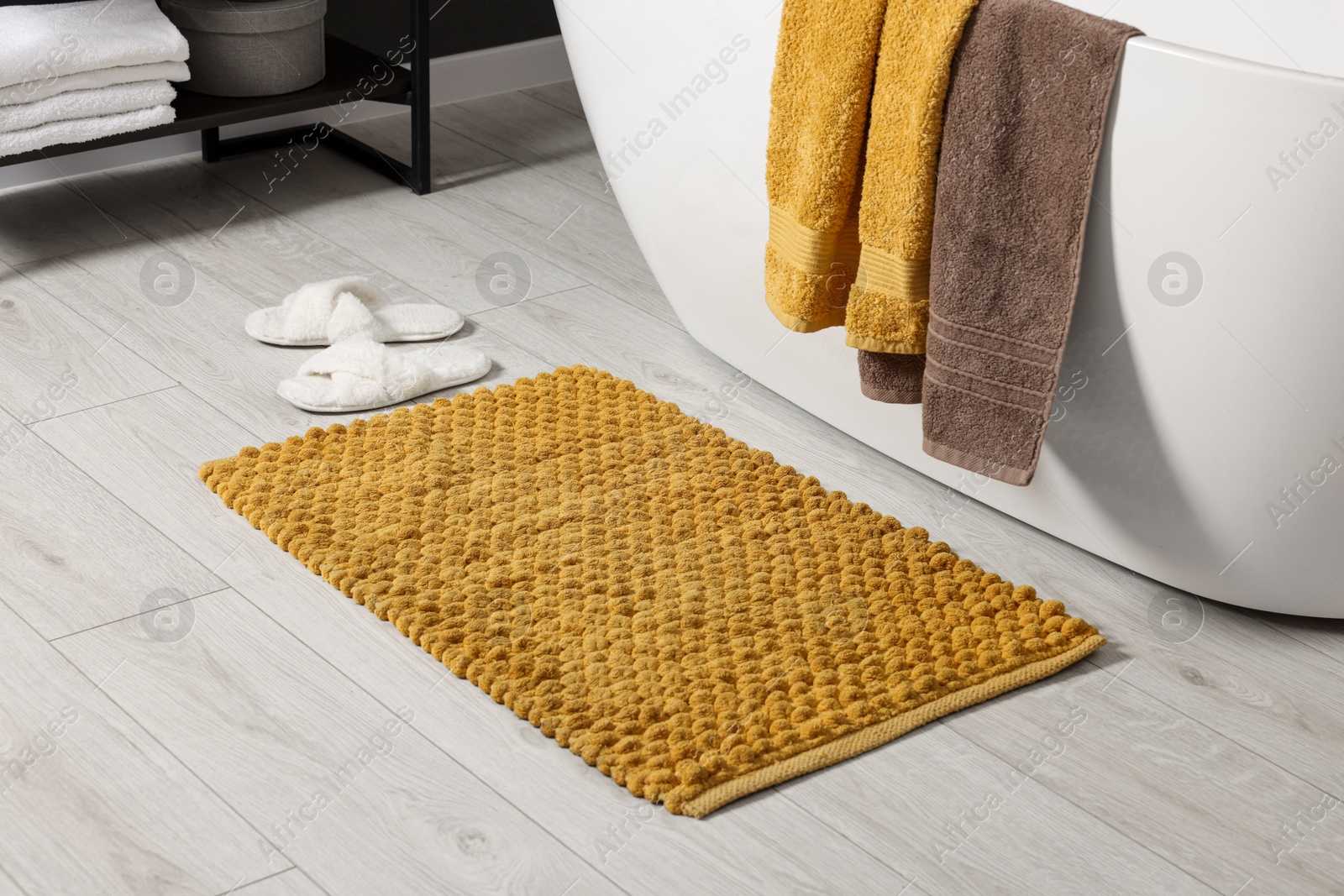 Photo of Soft yellow mat near tub in bathroom