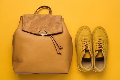 Stylish backpack and shoes on yellow background, flat lay