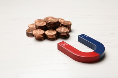 Photo of Magnet attracting coins on wooden background. Business concept