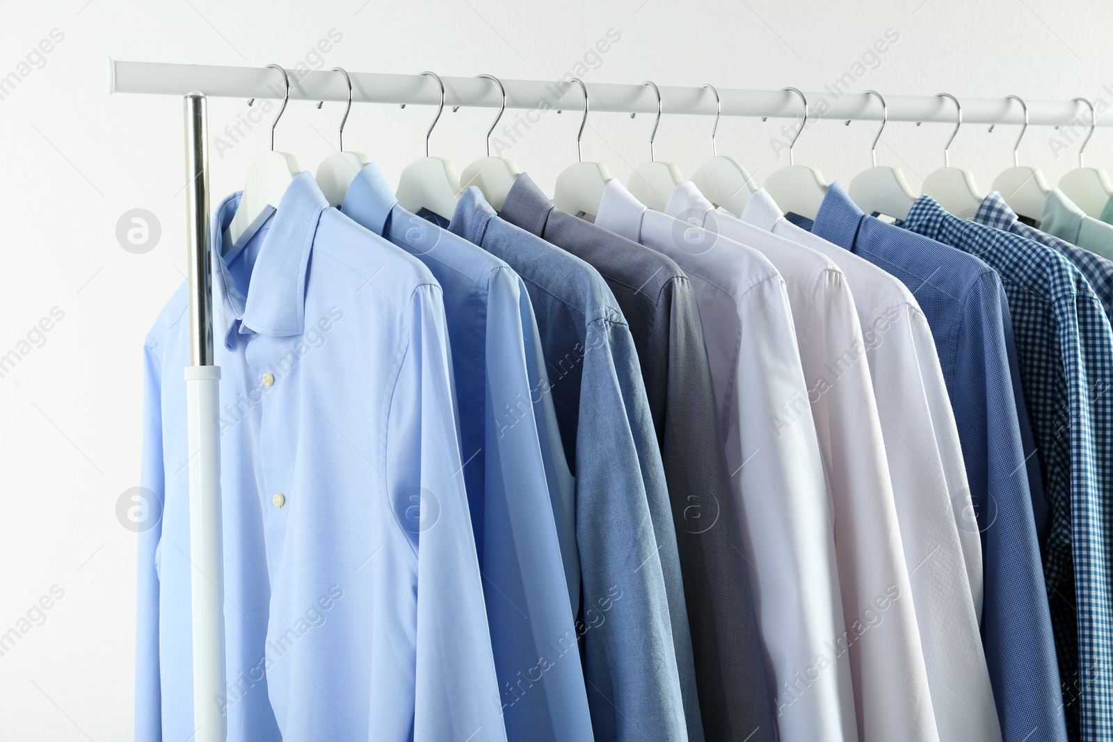 Photo of Men's clothes hanging on wardrobe rack against white background