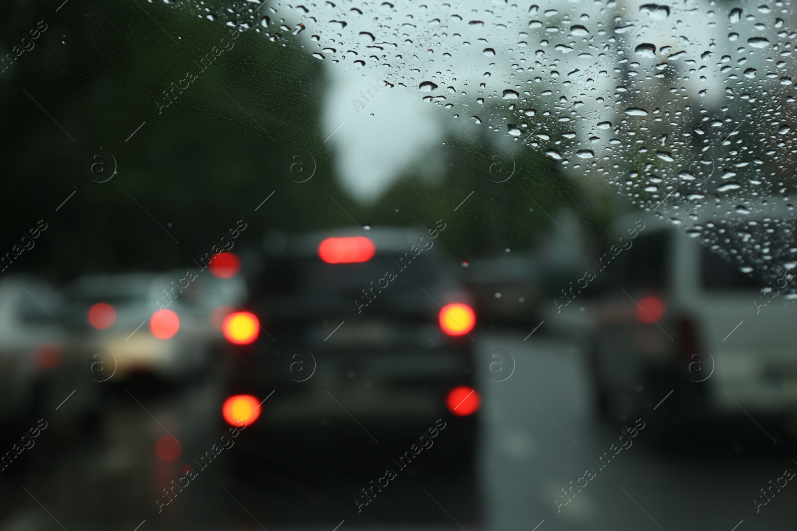 Photo of Blurred view of road through wet car window. Rainy weather