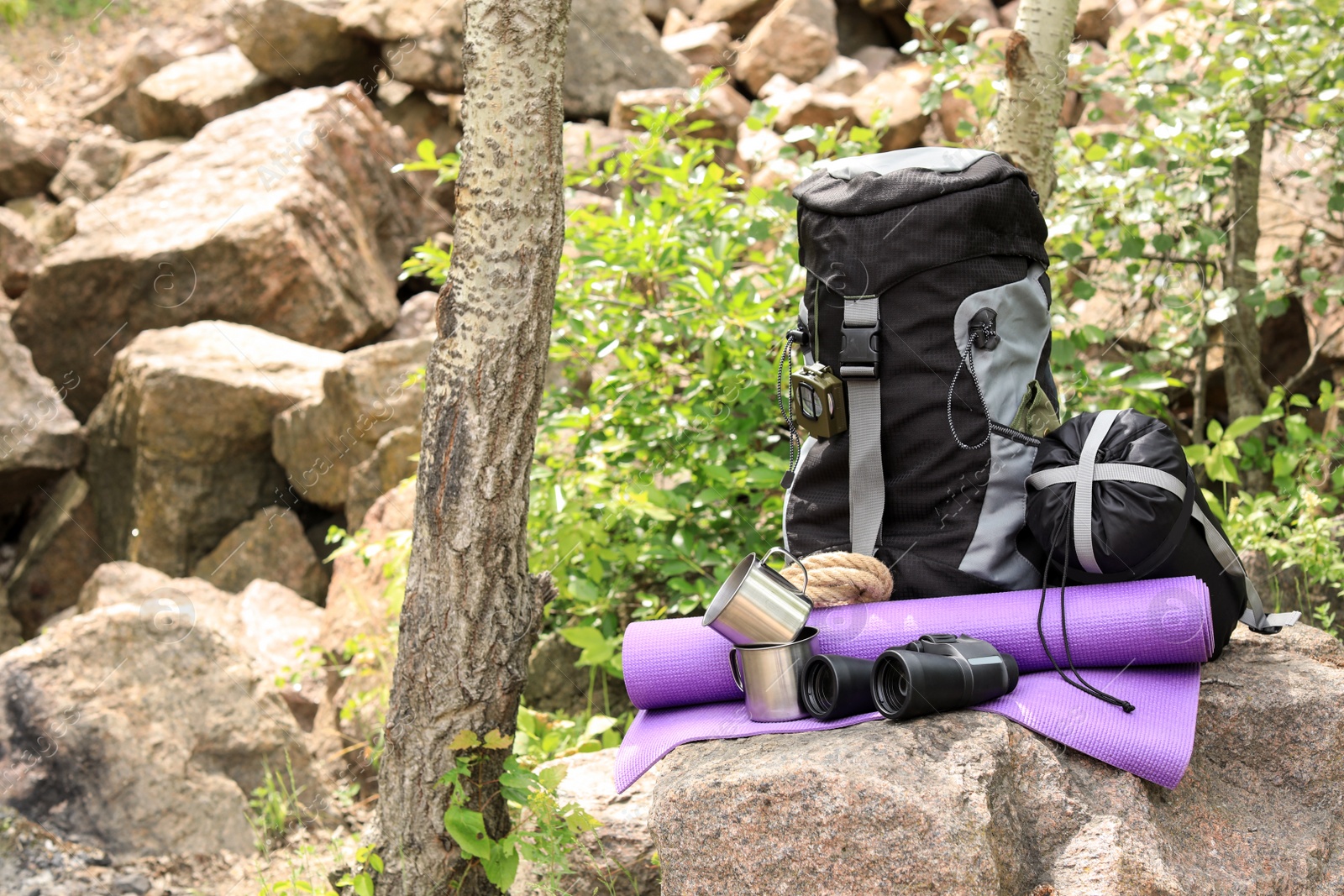 Photo of Backpack and camping equipment on stone in forest. Space for text