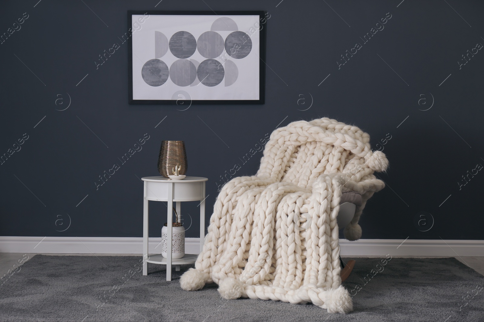Photo of Rocking chair with white knitted plaid in room. Interior design